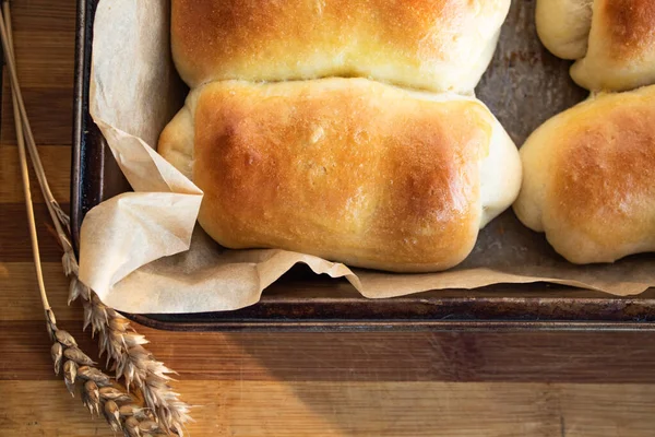 Ruddy buns in a baking tray on a wooden background — Stock Photo, Image