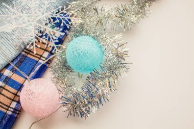 Toplardan, süs çiçeklerinden ve kar tanelerinden oluşan bir çelenk mavi bir kumaşın üzerinde yatıyor.