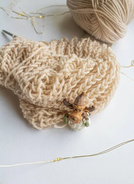 A ball of woolen thread with knitting needles and an English knitting pattern lie on a white background by the window with a small toy fawn — Stock Photo, Image