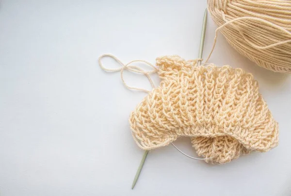 Une boule de fil de laine avec des aiguilles à tricoter et un motif de tricot anglais se trouvent sur un fond blanc près de la fenêtre — Photo