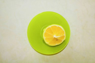 Yeşil bir tabağın üzerinde yarım bir limon yatıyor. 