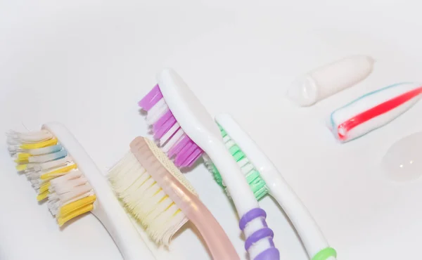 Used toothbrushes of different colors next to traces of toothpaste — Stock Photo, Image