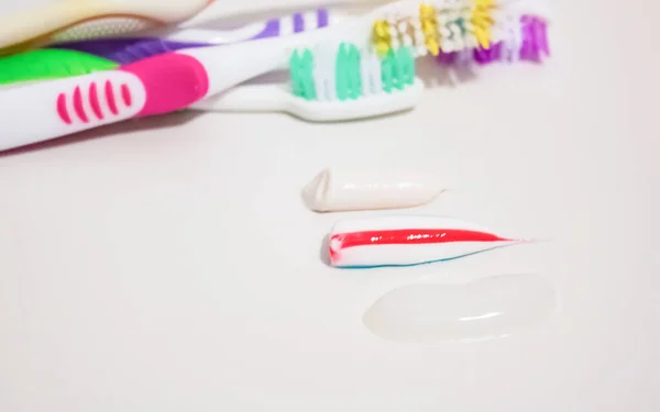 Три зразки зубної пасти на тлі зубних щіток — стокове фото