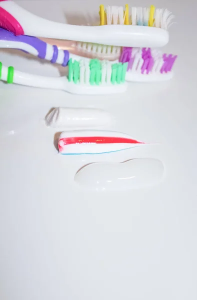 Three samples of toothpaste against the background of toothbrushes — Stock Photo, Image