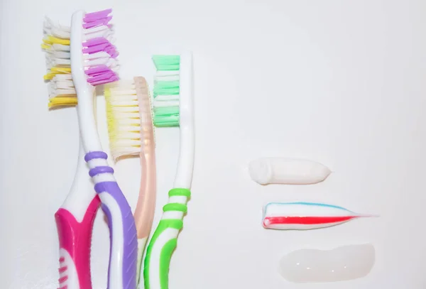 Toothbrushes of different colors next to traces of toothpaste — Stock Photo, Image