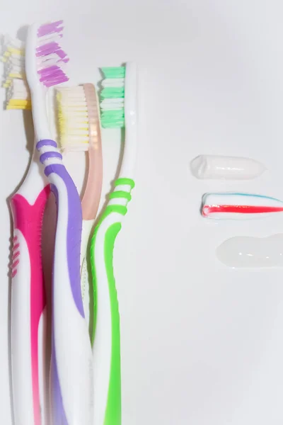 Toothbrushes of different colors next to traces of toothpaste — Stock Photo, Image