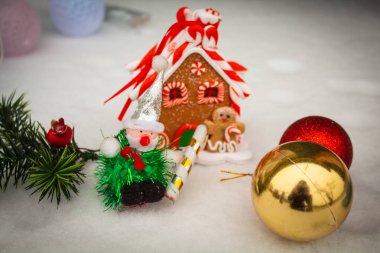 Yılbaşı oyuncağı zencefilli çöreğin yanında ve Noel topları karda