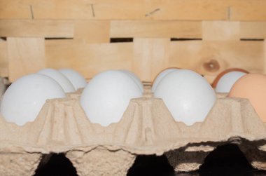 Tavuk yumurtaları beyaz arka planda yuvarlak bir hasır sepete konur.