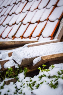 Binanın arka planındaki tahta tahtalar ve kirişler karla kaplı kırmızı kiremitlerle kaplı. 