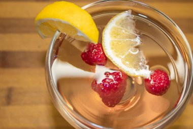 Bir dilim limonla süslenmiş ahududu meyveli pembe şaraplı kokteyl. 