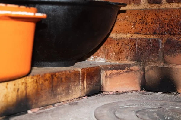 Caldeirões de ferro fundido ficam de perto em um forno da aldeia — Fotografia de Stock