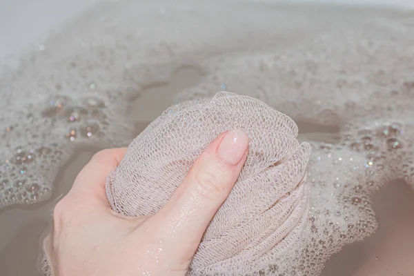 Een vrouw houdt een beige washandje vast tijdens huidverzorging in de badkamer — Stockfoto