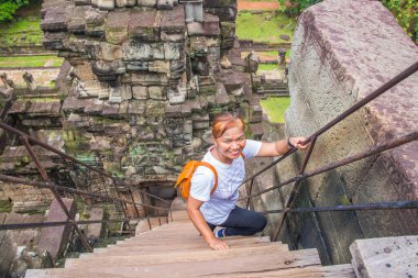 Angkor ne Siem Reap Kamboçya AsiaThai kadını coşkuyla tapınağa tırmanıyor.