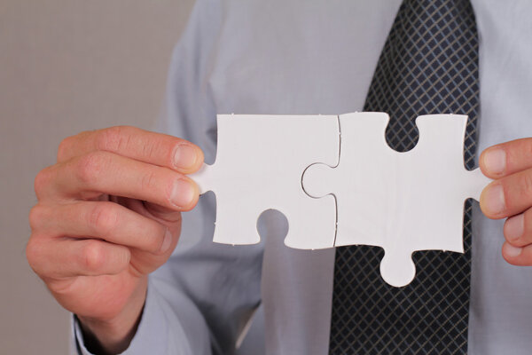 Бизнес-решения, концепция партнерства. Бизнесмен держит в руках два кусочка головоломки
