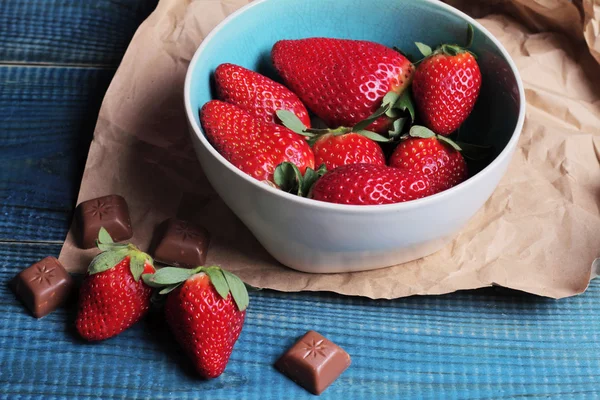 Erdbeerschüssel und Schokolade auf blauem, rustikalem Tisch, süße Wüste — Stockfoto