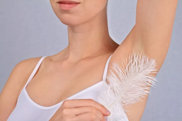 Armpit waxing, laser hair removal. Young woman holding her arms up and showing underarms, armpit, ideal smooth clear skin 图库照片