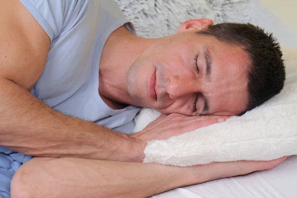 Спящий мужчина: Молодой красивый мужчина спит комфортно в постели — стоковое фото