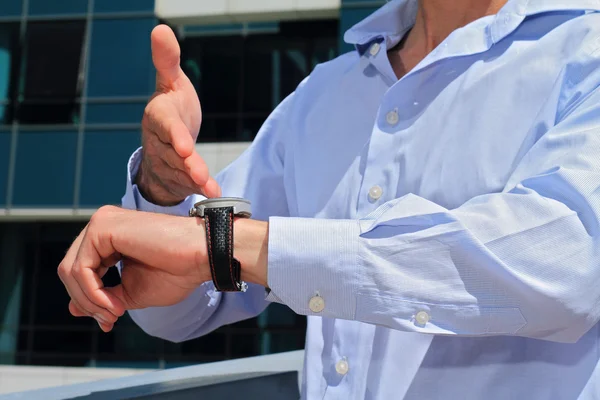 Hombre de negocios mostrando el tiempo en su reloj. Llegar tarde concepto —  Fotos de Stock