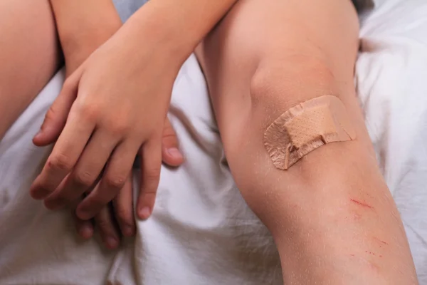 Child Pwith Band-Aid On His Knee. Criança com um gesso no joelho ferido de perto . — Fotografia de Stock