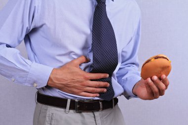 Businessman having stomachache because of eating junk food. Chronic gastritis or Ulcer. clipart