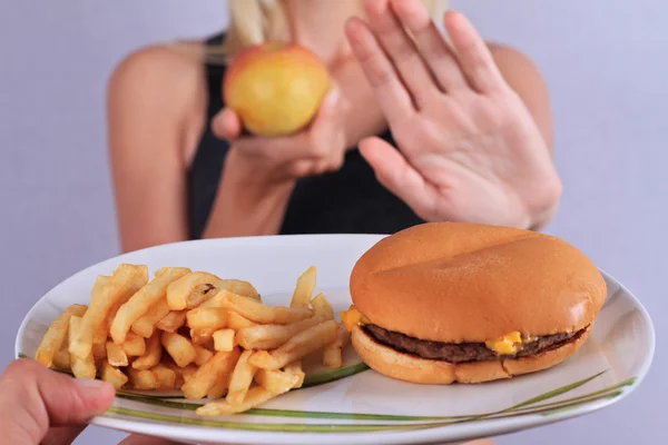 Kvinna vägrar att äta skräpmat och välja frukter. Hälsosam kost och aktiv livsstilskoncept — Stockfoto