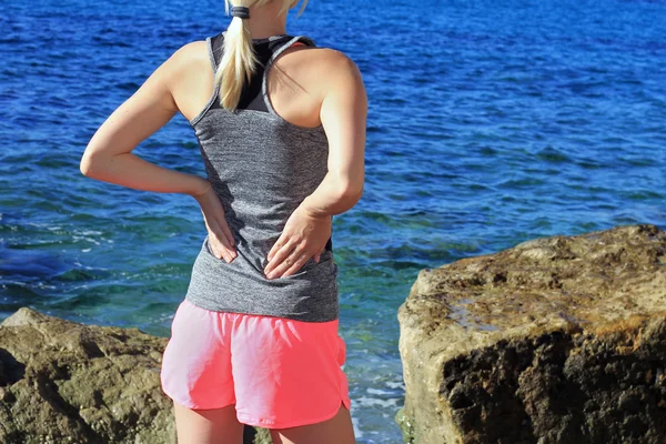 Dolor de espalda. Mujer atlética de fitness frotando los músculos de su espalda baja. Lesiones deportivas . — Foto de Stock