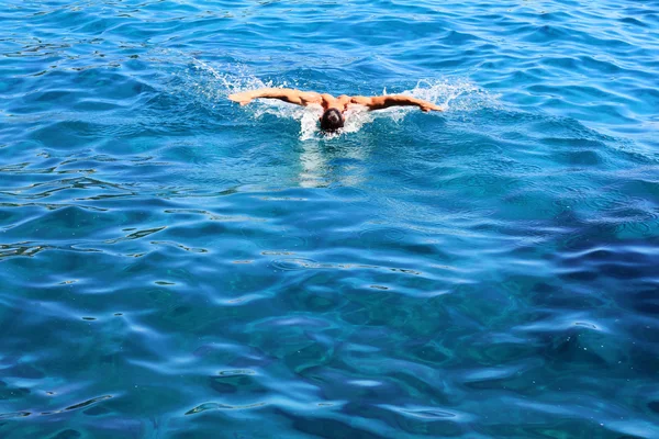 Strong athletic man swimming butterfly style in the sea. Active summer holiday vacation. Sport, healthy lifestyle concept — Stock Photo, Image