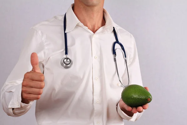 Doctor sosteniendo aguacate y haciendo pulgares hacia arriba. Concepto de salud, prevención de la hipertensión — Foto de Stock