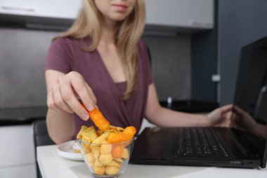 Bilgisayarda çalışan, fast food ve abur cubur yiyen bir kadın. Sağlıksız Yaşam Tarzı