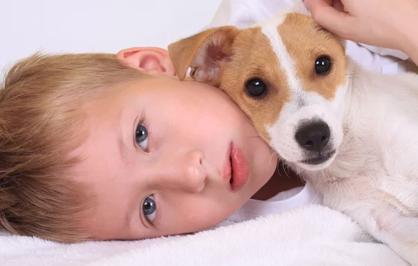 Mladý chlapec objímání psa v posteli — Stock fotografie