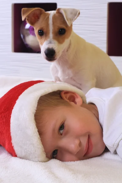 Niño vistiendo sombrero de santa y su perro — Foto de Stock