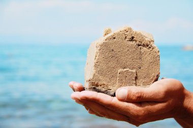 Eve gelen kum yapılmış holding eller üzerinde kapatın. Sahil evi. Yaz tatil, tatil, kartpostal, arka plan. Gayrimenkul yatırım kavramı