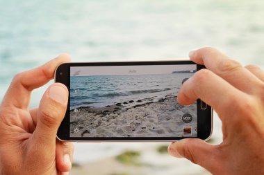 Yalı mobil cep telefonu ile fotoğraf çekici erkek ellerinde kapatın. Yaz plaj tatil tatil kavramı