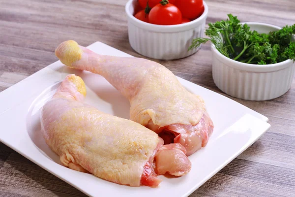 Pernas de frango cruas decoradas com salada e tomate cereja em prato branco. Alimentos dietéticos, estilo de vida saudável — Fotografia de Stock