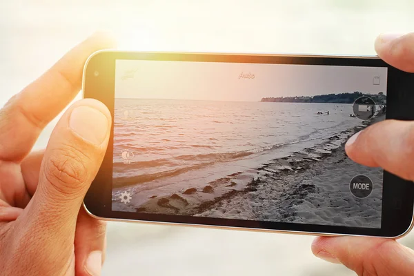 Închideți mâinile de sex masculin care fotografiază coasta mării cu telefonul mobil. Conceptul de vacanță pe plajă de vară. Culorile apusului — Fotografie, imagine de stoc