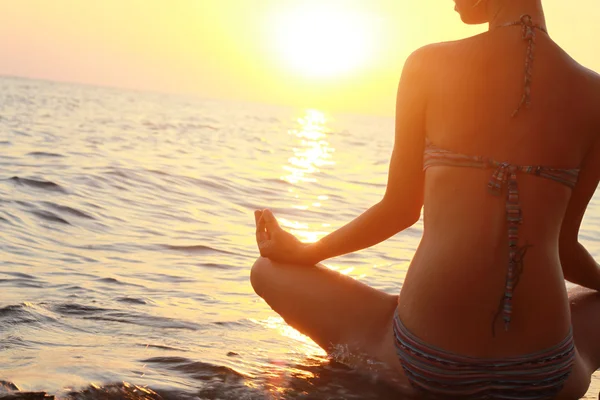Joga kobieta meditatiing w pozie Lotos na plaży podczas zachodu słońca — Zdjęcie stockowe