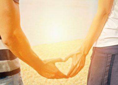 Couple in love Making Heart Shape With  hands on the beach. Love, relationship, happiness, summer, vacatioon, honey moon, holidays concept