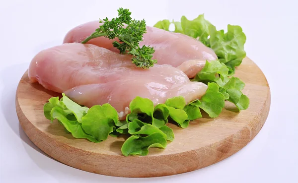 Filetes de peito de frango cru decorados com salada em tábua de corte de madeira. Alimentos dietéticos, estilo de vida saudável — Fotografia de Stock