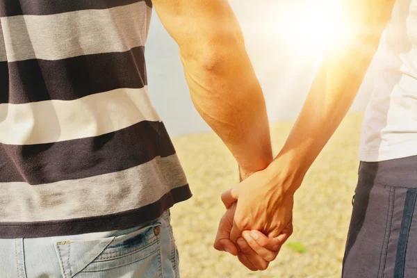 Joven pareja de hombres y mujeres caminando de la mano en una playa. Amor, relación, felicidad, verano, vacaciones, luna de miel, concepto de vacaciones — Foto de Stock