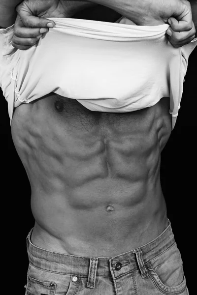 Homens musculosos, corpo perfeito, abdominais, seis alcateias. Um atlético forte de jeans a mostrar o abdómen. Musculação, esporte, fitness, treino, conceito de estilo de vida ativo. Foto em preto e branco — Fotografia de Stock