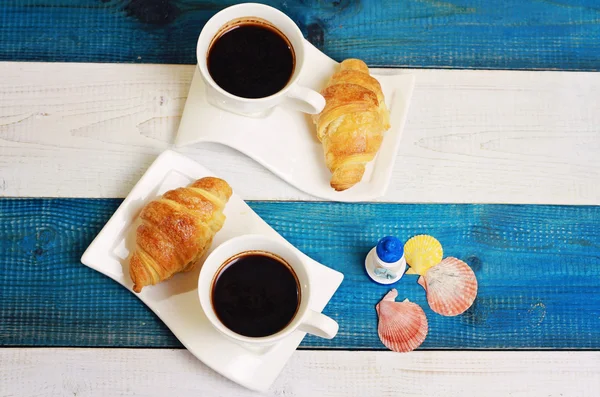 Dos tazas de café, croissants y flores sobre fondo marino rústico blanco y azul. Concepto de desayuno de vacaciones —  Fotos de Stock