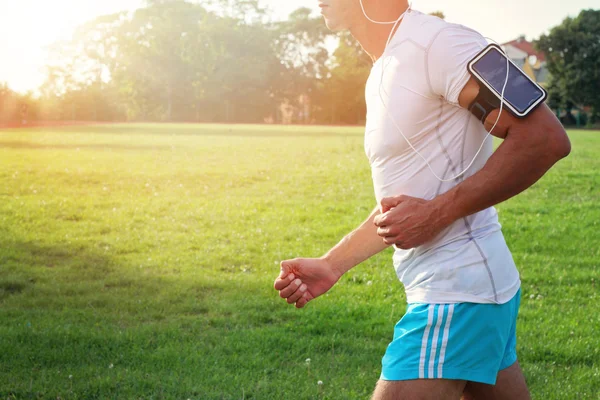 Un uomo che corre nel parco, nella foresta. Maschio corridore ascoltare musica su — Foto Stock