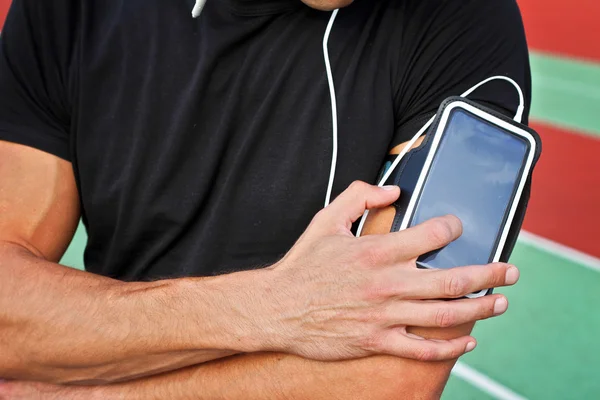 Мужчина бегун с мобильным смартфоном, слушает музыку во время тренировки. Бег, бег трусцой, кардио, спорт, активный образ жизни — стоковое фото
