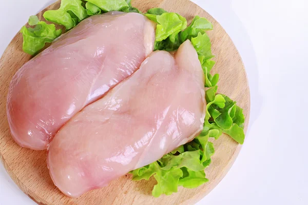 Filetes de peito de frango cru decorados com salada em tábua de corte de madeira. Alimentos dietéticos, estilo de vida saudável Imagem De Stock