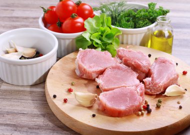 Taze çiğ domuz fileto madalyon salata, zeytin yağı ve ahşap kesme tahtası üzerinde kiraz domates ile. Sağlıklı yaşam tarzı