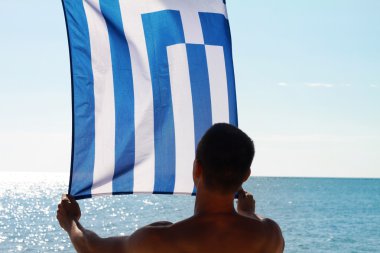 Silhouette of Man holding Greek flag. Man holding  flag of Greece in front of sea