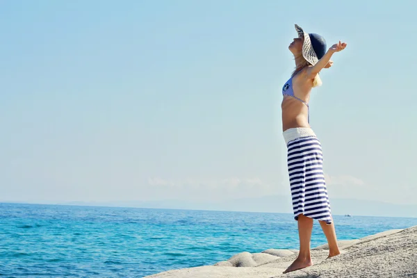 Atractiva mujer rubia con sombrero de paja respirando feliz con los brazos levantados, concepto de libertad, mar, sol, verano, hodiday, vacaciones . — Foto de Stock