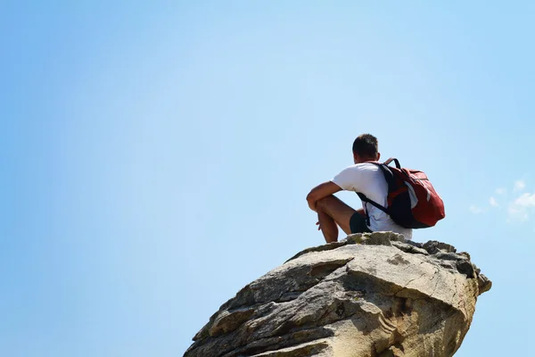 Jeune homme assis et ayant un repos au sommet d'une montagne — Photo