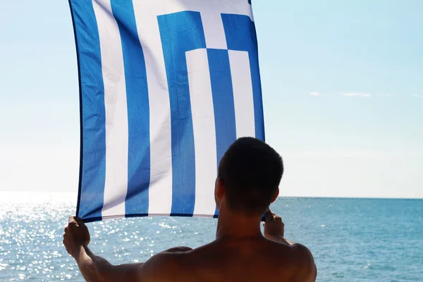 Silhouette of Man holding Greek flag. Man holding  flag of Greece in front of sea — Φωτογραφία Αρχείου