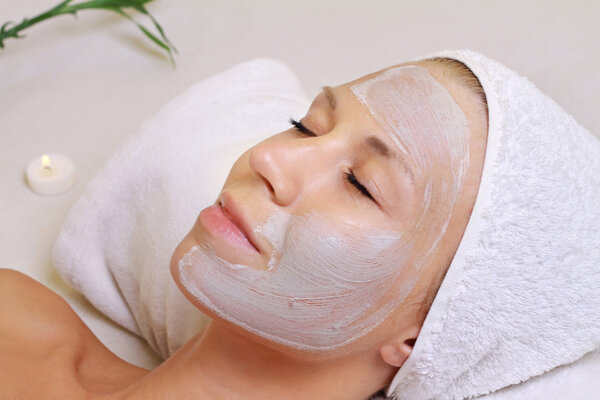 Young beautiful girl receiving clay facial mask in spa beauty sa
